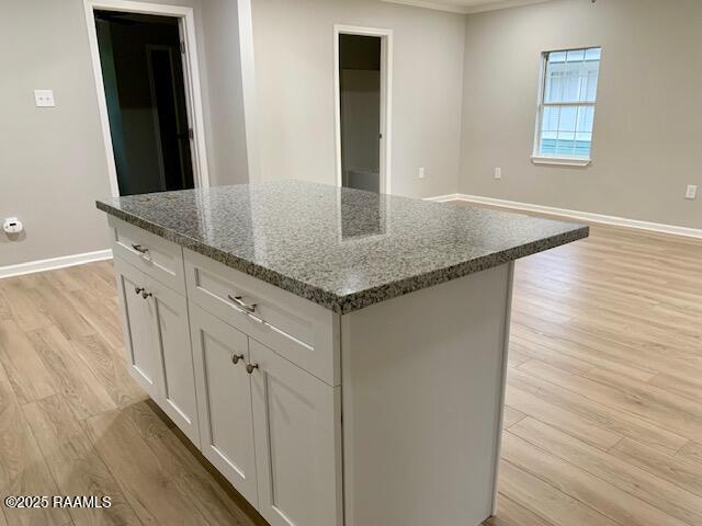 kitchen with baseboards, light wood-type flooring, white cabinets, and a center island