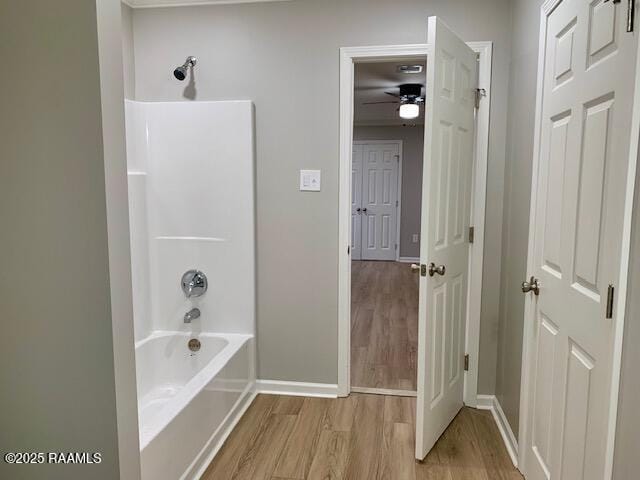 full bath with ceiling fan,  shower combination, wood finished floors, and baseboards