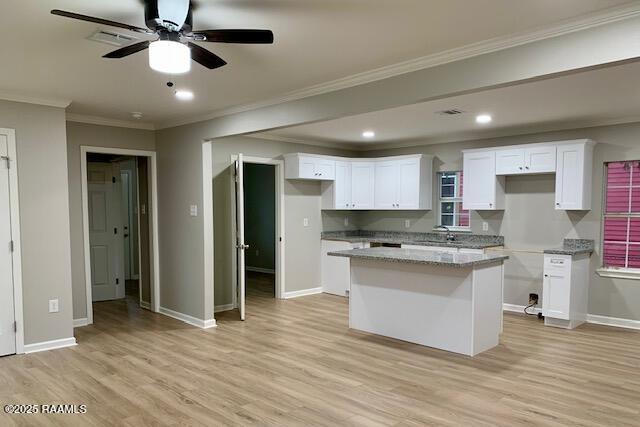 kitchen with a center island, crown molding, light wood-style flooring, white cabinets, and baseboards