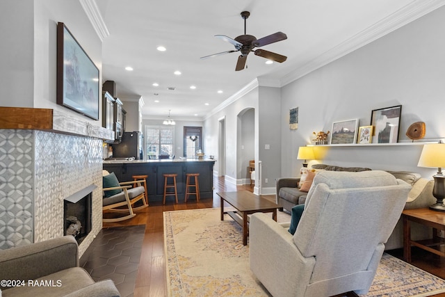 living room featuring a fireplace, ceiling fan, ornamental molding, and dark wood-type flooring