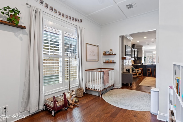 bedroom with a brick fireplace, dark hardwood / wood-style flooring, a nursery area, and multiple windows