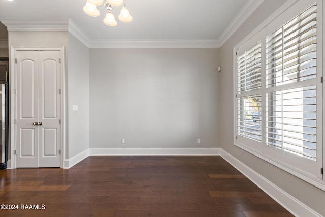 spare room featuring a notable chandelier, dark hardwood / wood-style floors, and ornamental molding