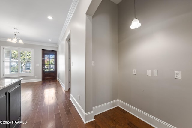 hall featuring crown molding, dark wood-type flooring, and a notable chandelier