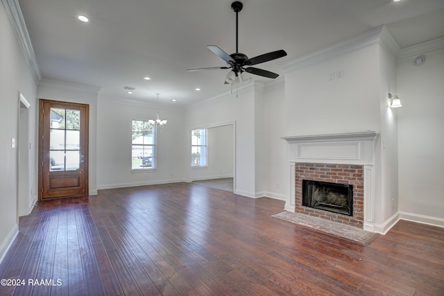 unfurnished living room featuring a fireplace, ceiling fan with notable chandelier, dark hardwood / wood-style floors, and ornamental molding