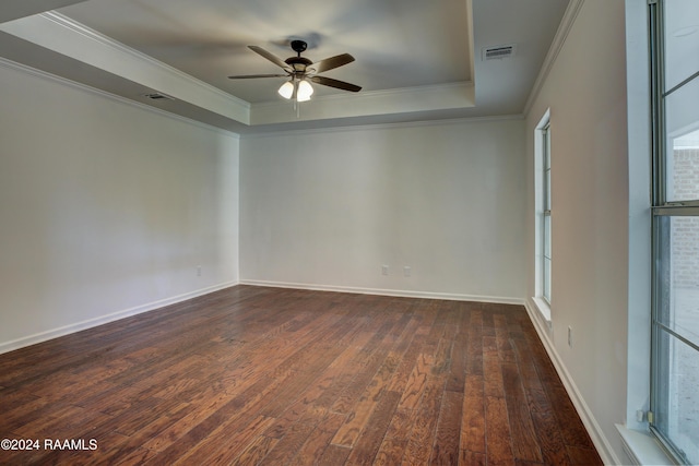 unfurnished room featuring a raised ceiling, ceiling fan, dark hardwood / wood-style flooring, and ornamental molding