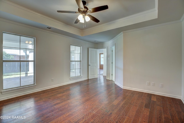 empty room with dark hardwood / wood-style floors, ceiling fan, crown molding, and a tray ceiling