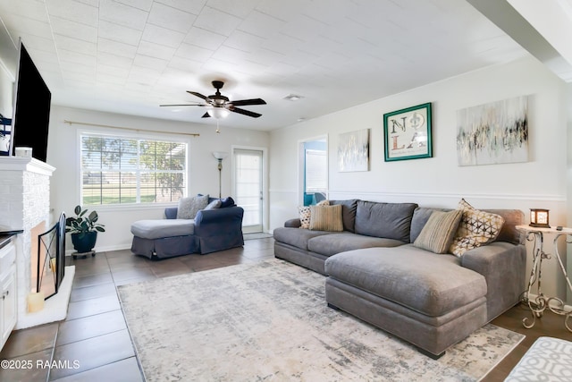 tiled living room with ceiling fan and a fireplace