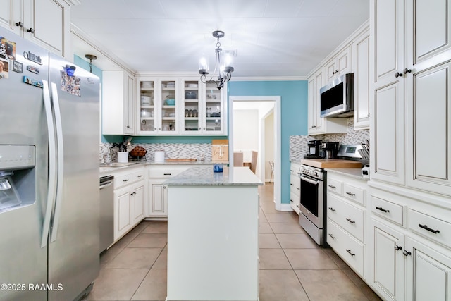 kitchen featuring white cabinets, light tile patterned floors, decorative light fixtures, a kitchen island, and stainless steel appliances