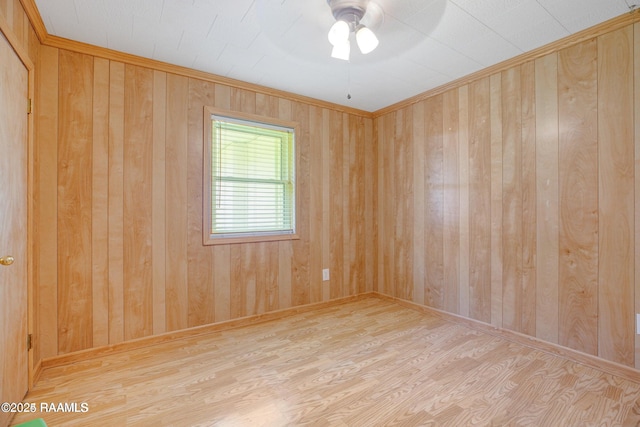 unfurnished room featuring ceiling fan, wood walls, light wood-type flooring, and crown molding