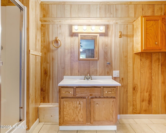 bathroom with tile patterned floors, vanity, wood walls, and a shower with door