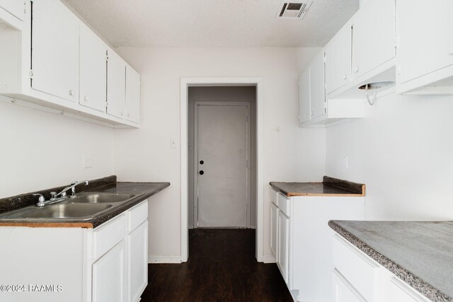 kitchen featuring sink, white cabinets, dark wood-type flooring, and a textured ceiling