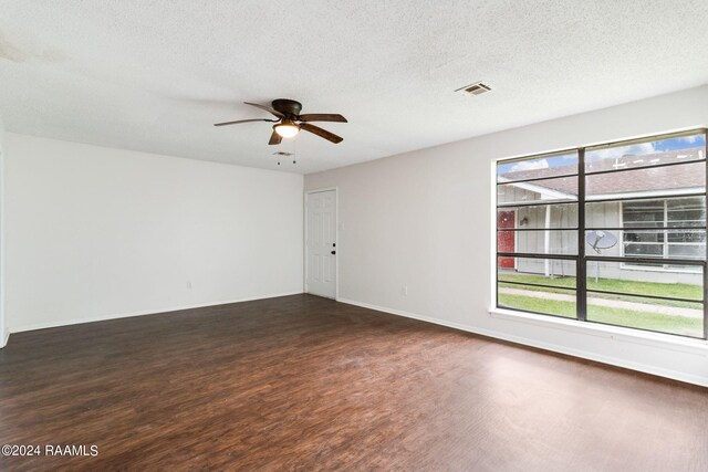 unfurnished room featuring a textured ceiling, a wealth of natural light, ceiling fan, and dark hardwood / wood-style floors