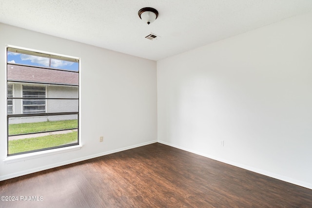 unfurnished room with a wealth of natural light, dark hardwood / wood-style flooring, and a textured ceiling