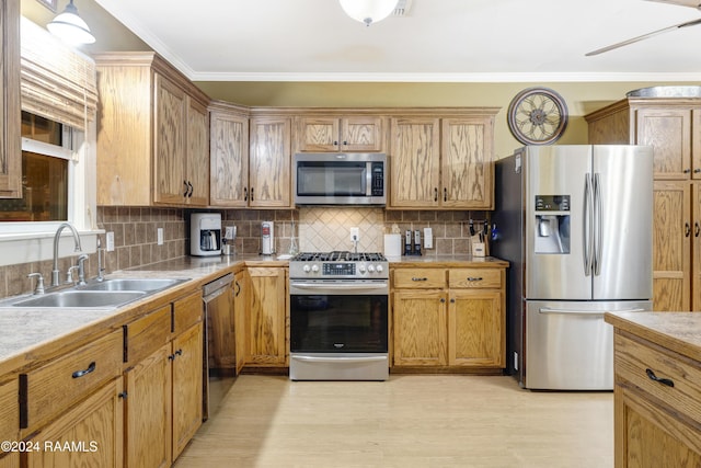 kitchen featuring sink, crown molding, light hardwood / wood-style flooring, stainless steel appliances, and tasteful backsplash