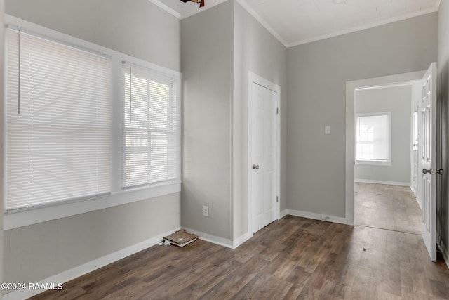 empty room with crown molding, plenty of natural light, and dark wood-type flooring