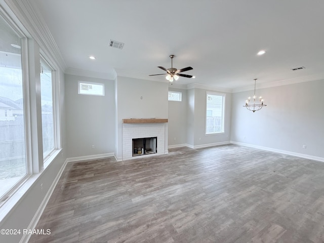 unfurnished living room featuring crown molding, wood-type flooring, ceiling fan with notable chandelier, and a brick fireplace