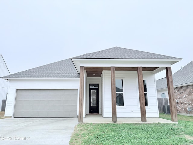 view of front of house featuring a garage, a front yard, and central air condition unit