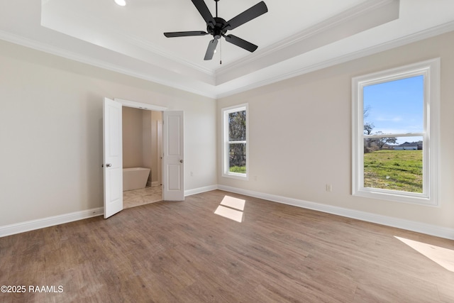 unfurnished bedroom featuring baseboards, a raised ceiling, and wood finished floors