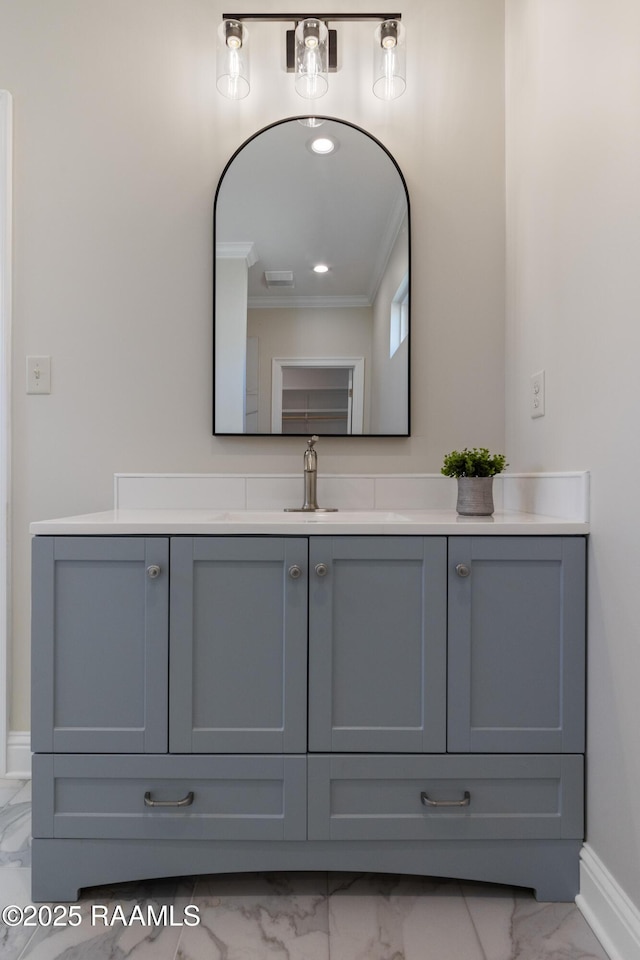 bathroom featuring marble finish floor, ornamental molding, vanity, and baseboards