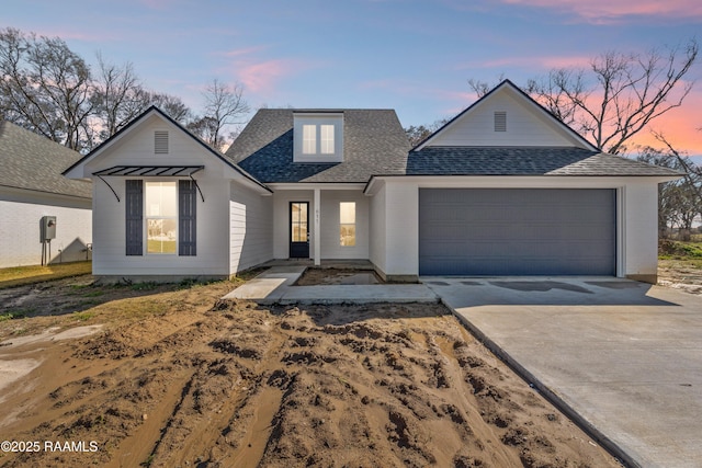 view of front of property with an attached garage, concrete driveway, and roof with shingles