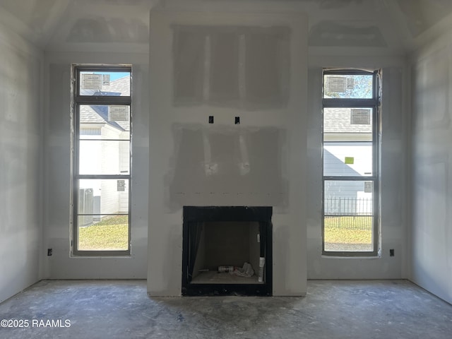 unfurnished living room with a fireplace, a wealth of natural light, and concrete floors