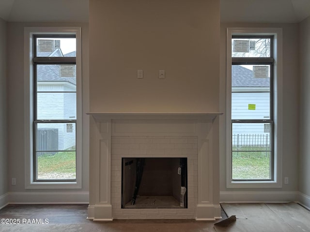 unfurnished living room featuring a brick fireplace, hardwood / wood-style floors, and plenty of natural light