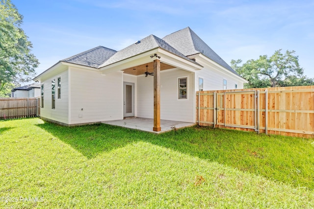 back of house featuring ceiling fan, roof with shingles, a lawn, a patio area, and a fenced backyard