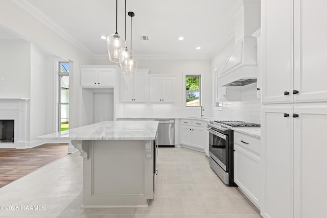 kitchen with crown molding, appliances with stainless steel finishes, a center island, white cabinetry, and decorative backsplash