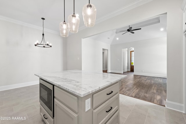 kitchen with crown molding, a center island, built in microwave, white cabinets, and ceiling fan with notable chandelier