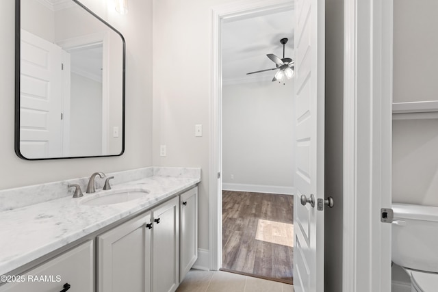 bathroom featuring vanity, toilet, a ceiling fan, baseboards, and ornamental molding