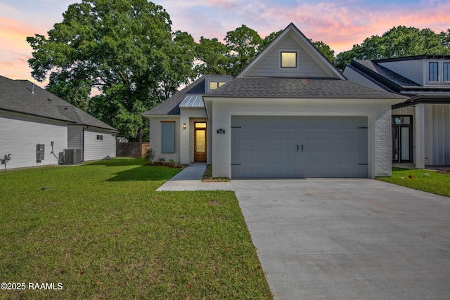 view of front of property featuring driveway, a front yard, central AC, an attached garage, and a shingled roof