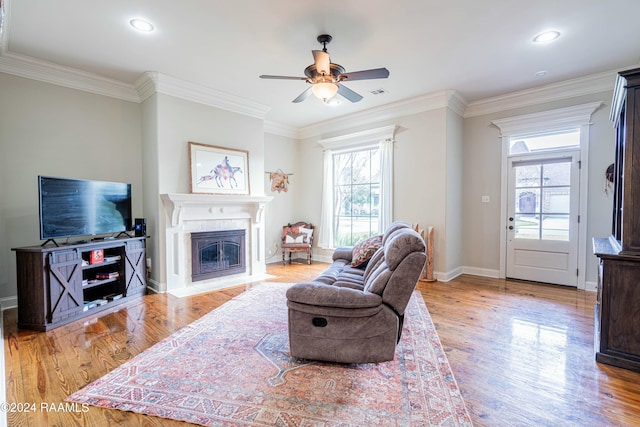 living room featuring light hardwood / wood-style floors, plenty of natural light, crown molding, and ceiling fan