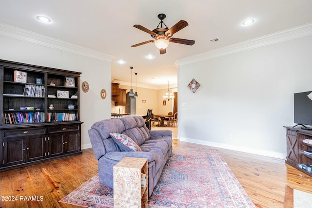 living room featuring ceiling fan with notable chandelier, light hardwood / wood-style flooring, and crown molding