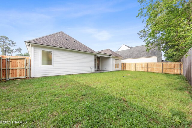 back of house featuring a fenced backyard, a shingled roof, and a yard
