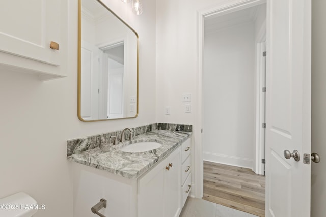 half bathroom featuring tile patterned floors, toilet, baseboards, vanity, and ornamental molding