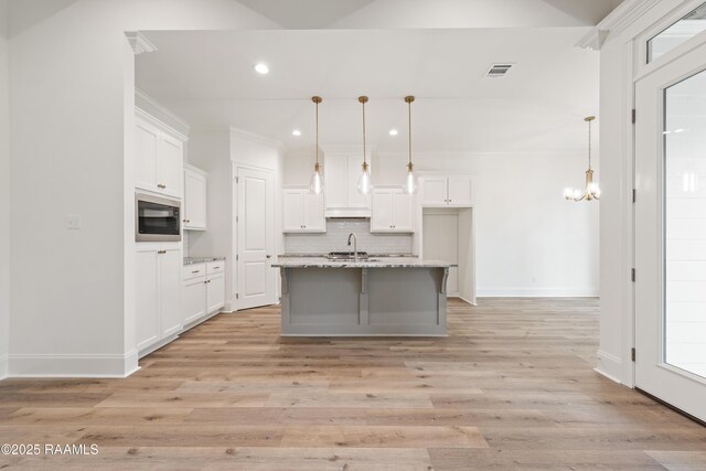 kitchen featuring white cabinets, built in microwave, tasteful backsplash, recessed lighting, and under cabinet range hood