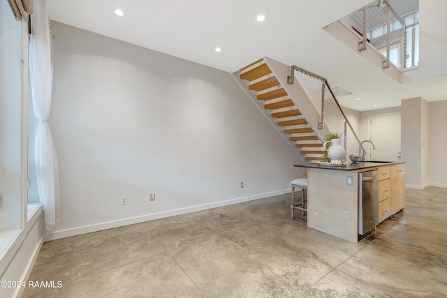 kitchen with sink, light brown cabinets, stainless steel dishwasher, a breakfast bar area, and a kitchen island with sink