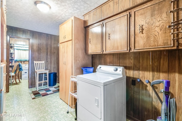 washroom with washer / clothes dryer, wood walls, and cabinets