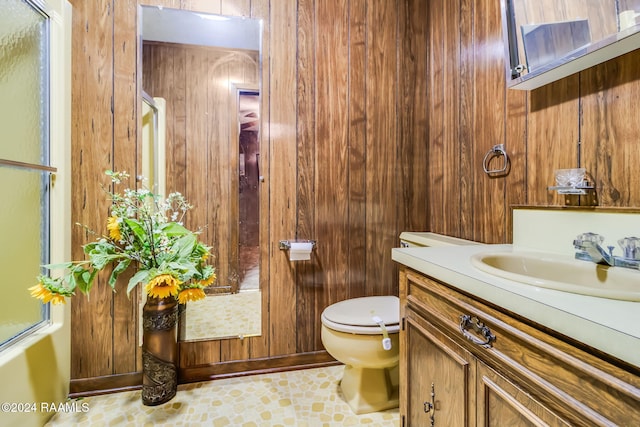 bathroom featuring tile patterned flooring, vanity, toilet, and wooden walls