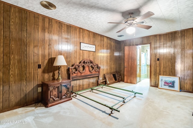 bedroom with ensuite bath, wood walls, carpet floors, and ceiling fan