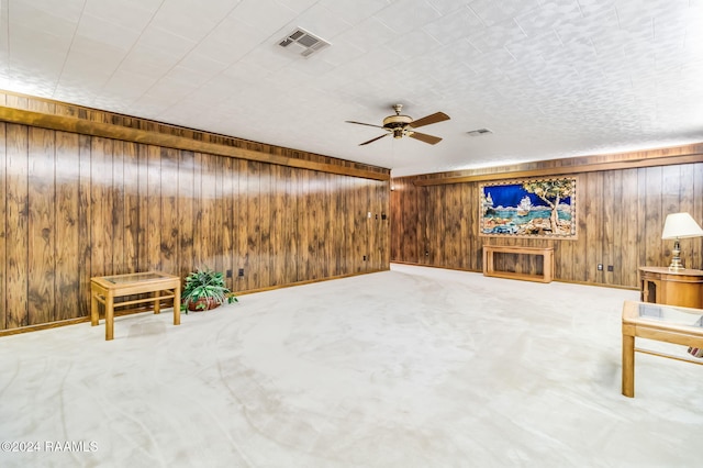 unfurnished room with ceiling fan, carpet floors, and wooden walls