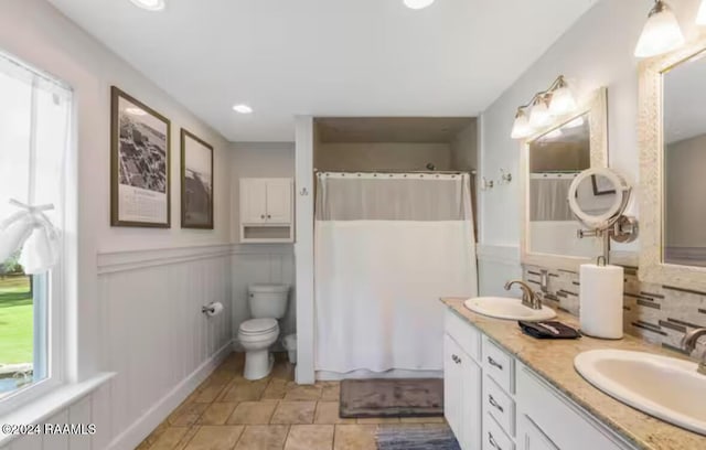 bathroom with backsplash, vanity, toilet, and walk in shower