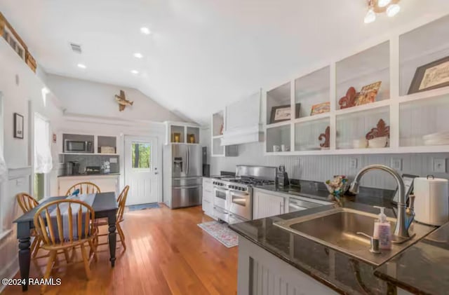 kitchen with sink, vaulted ceiling, hardwood / wood-style flooring, appliances with stainless steel finishes, and white cabinetry