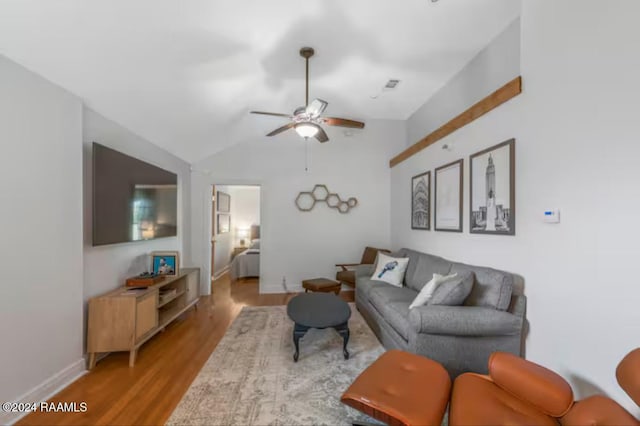 living room featuring ceiling fan, light wood-type flooring, and vaulted ceiling