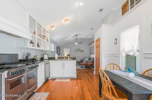 kitchen featuring ceiling fan, kitchen peninsula, lofted ceiling, white cabinets, and light wood-type flooring