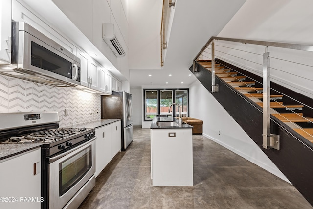 kitchen with white cabinetry, sink, tasteful backsplash, a kitchen island with sink, and appliances with stainless steel finishes