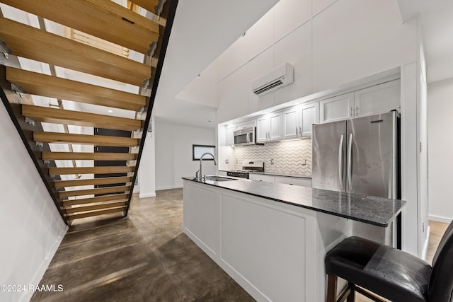 kitchen featuring stainless steel appliances, tasteful backsplash, a wall unit AC, a breakfast bar area, and white cabinets