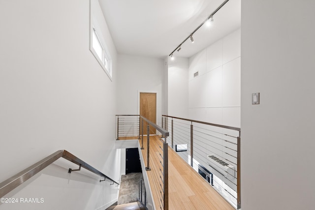 stairs with hardwood / wood-style flooring and track lighting