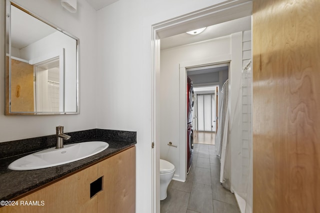 bathroom with tile patterned flooring, vanity, toilet, and washer / dryer