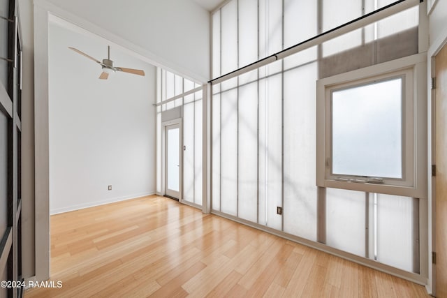 interior space featuring light wood-type flooring, a towering ceiling, a wealth of natural light, and ceiling fan